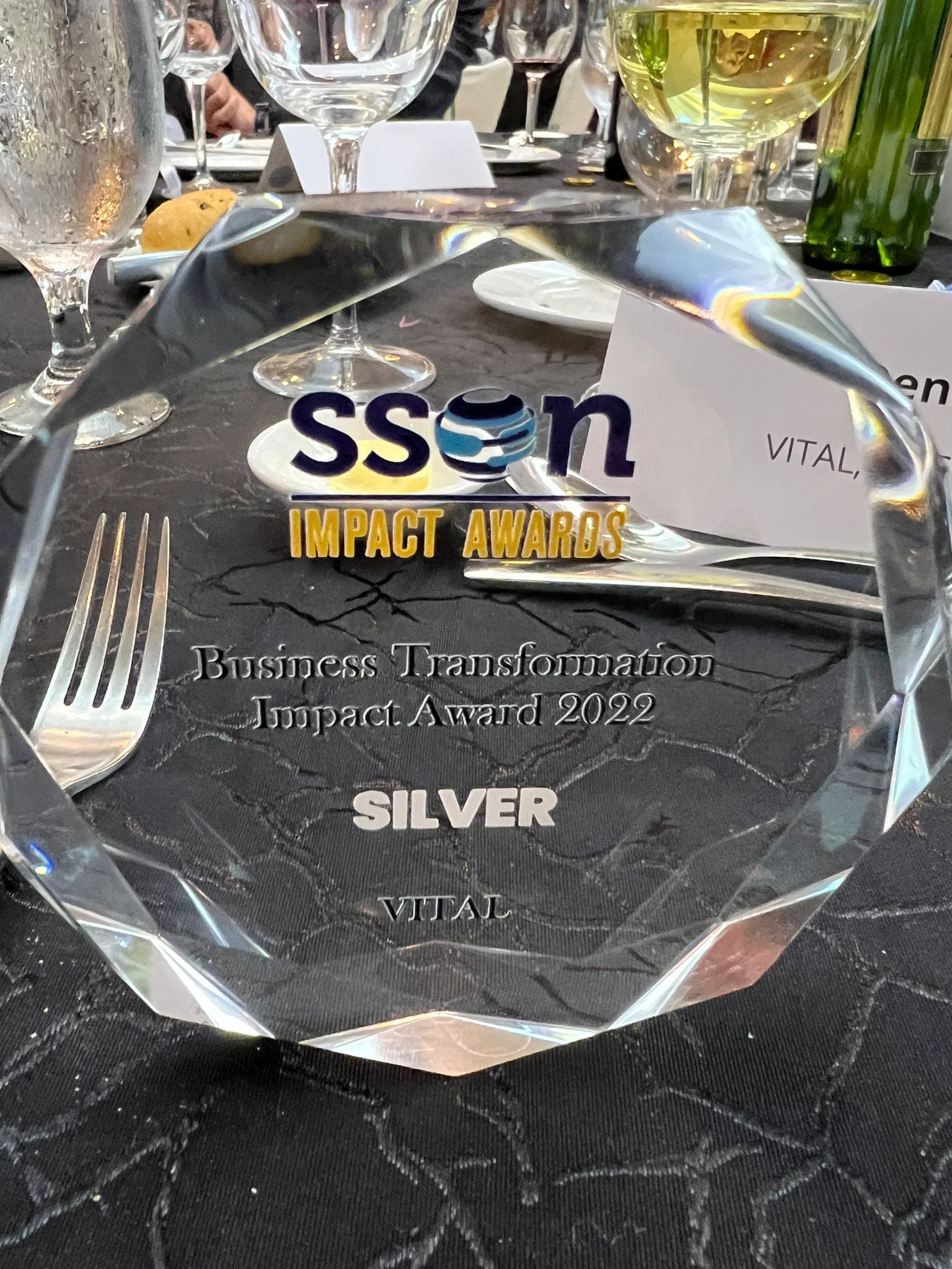Crystal octagonal SSON Impact Awards plaque for Business Transformation Silver Award 2022 awarded to Vital, on a dining table.